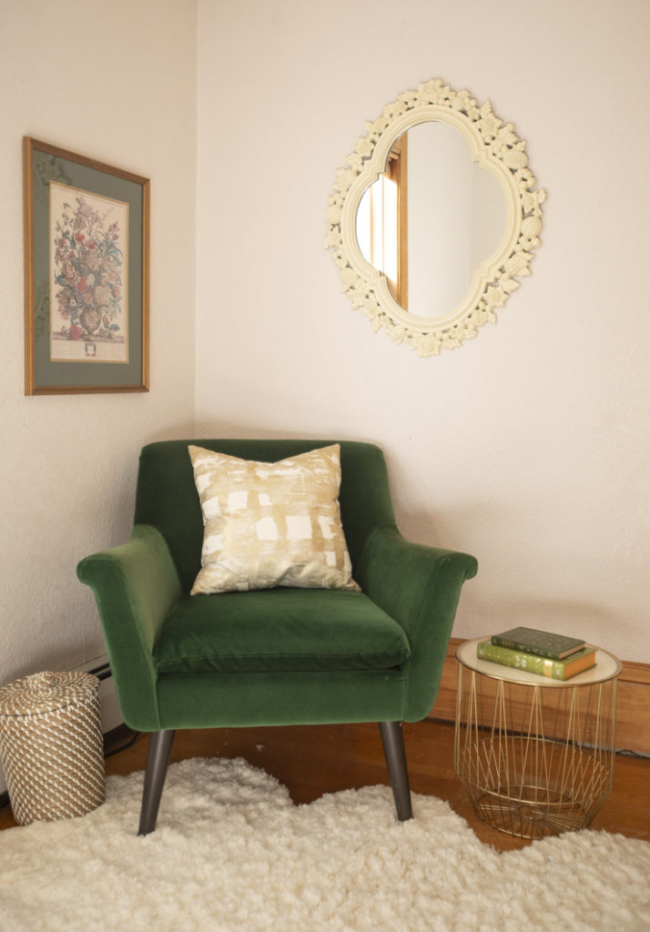 bedroom corner with green velvet chair and spray painted mirror