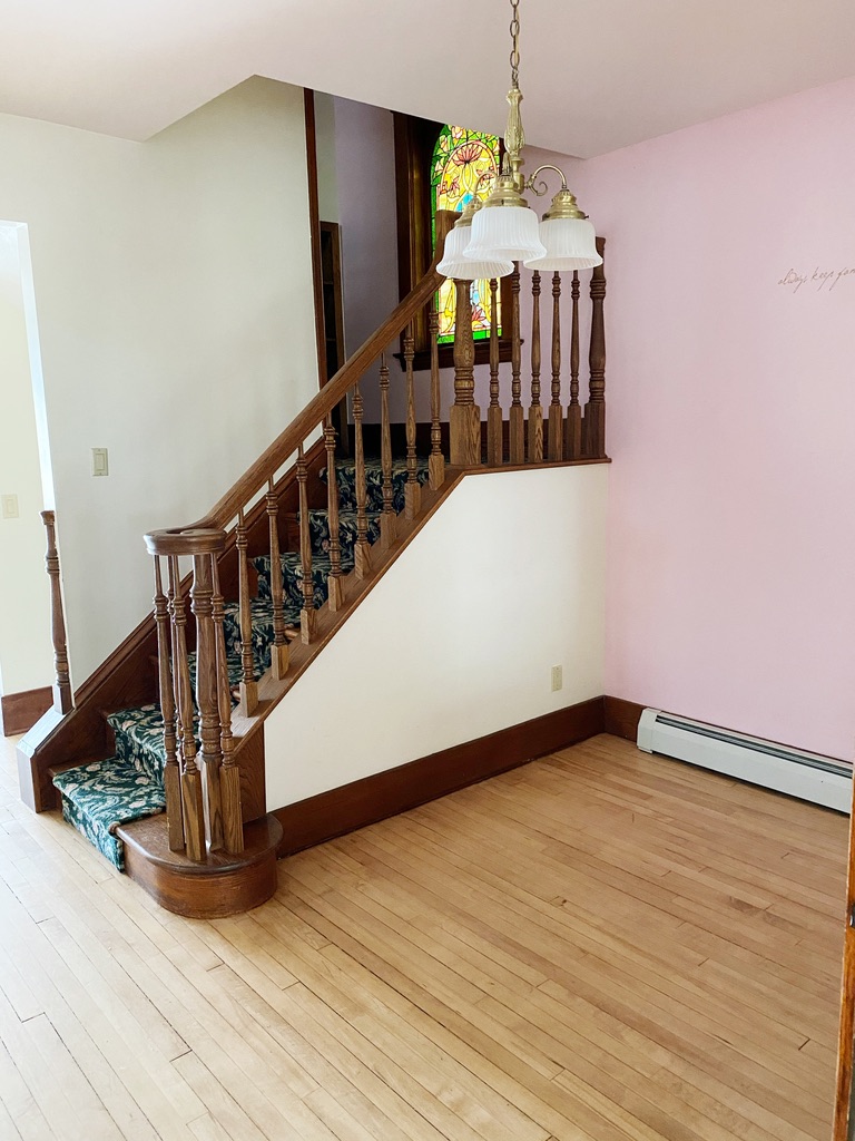 old house with wooden banister and pink wall